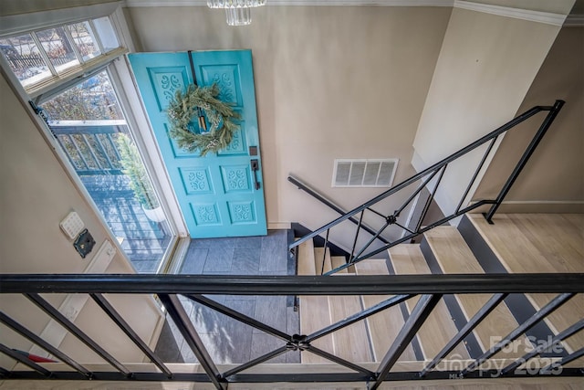 entrance foyer featuring hardwood / wood-style flooring, ornamental molding, and a chandelier