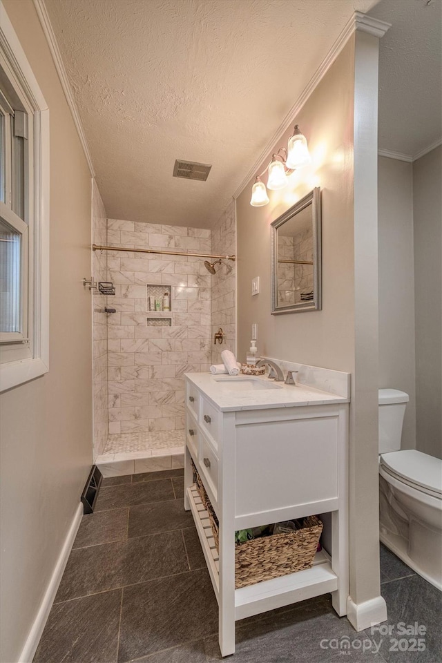 bathroom with tiled shower, toilet, a textured ceiling, ornamental molding, and vanity