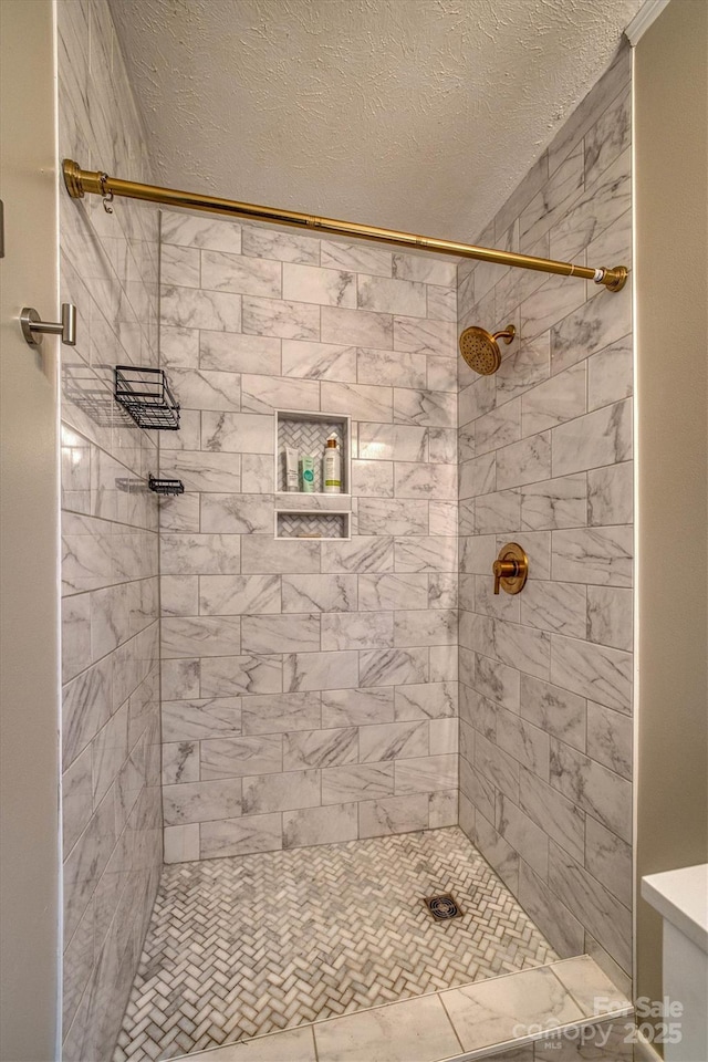 bathroom with a textured ceiling and a tile shower