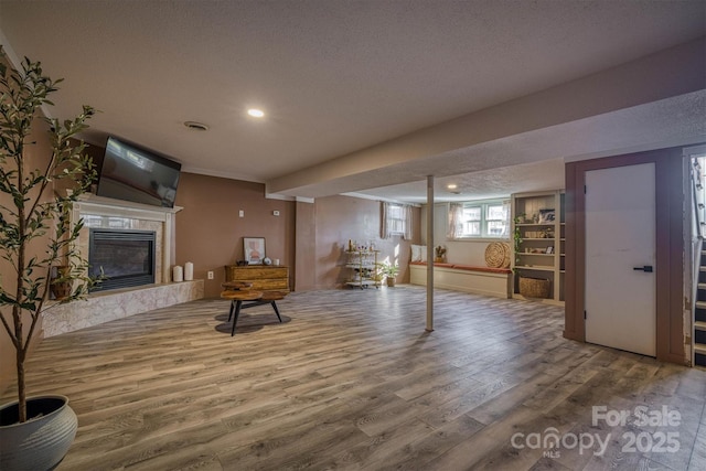 interior space with hardwood / wood-style flooring, a premium fireplace, and a textured ceiling