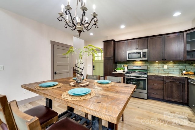 kitchen with decorative light fixtures, decorative backsplash, light hardwood / wood-style floors, stainless steel appliances, and dark brown cabinets