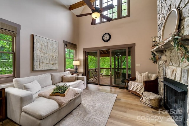 living room with ceiling fan, a fireplace, a healthy amount of sunlight, and light wood-type flooring