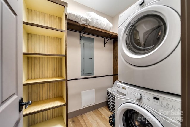 laundry room with stacked washing maching and dryer, electric panel, and light hardwood / wood-style floors