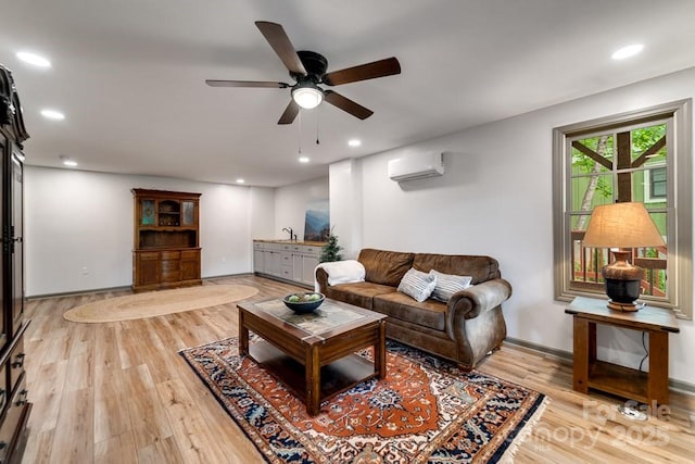 living room featuring an AC wall unit, sink, ceiling fan, and light hardwood / wood-style flooring