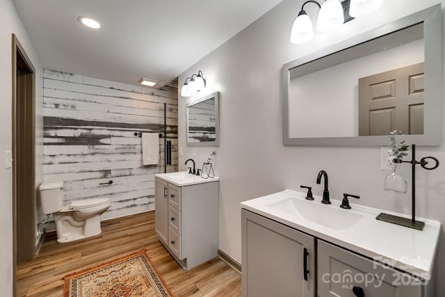 bathroom with vanity, wood-type flooring, toilet, and wood walls