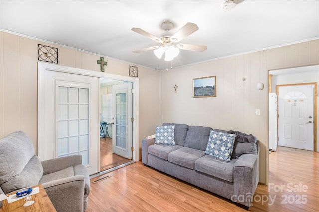 living room featuring light hardwood / wood-style flooring, ornamental molding, and ceiling fan