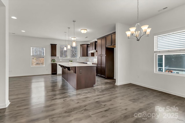 kitchen featuring a center island, a kitchen bar, a healthy amount of sunlight, and decorative light fixtures