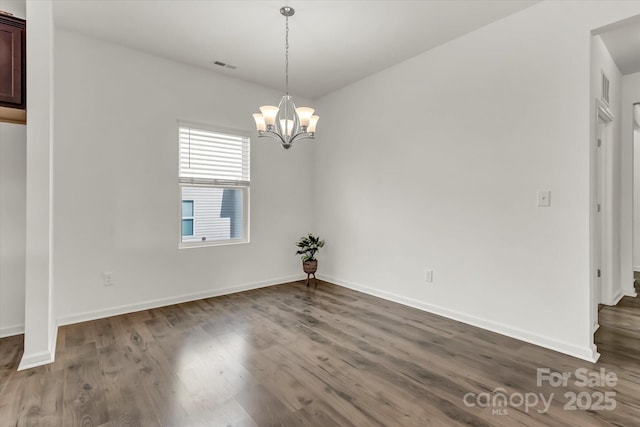 unfurnished dining area with dark hardwood / wood-style floors and an inviting chandelier