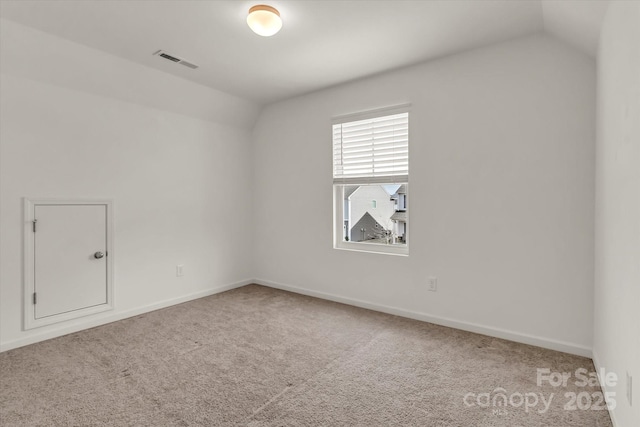 carpeted spare room with lofted ceiling