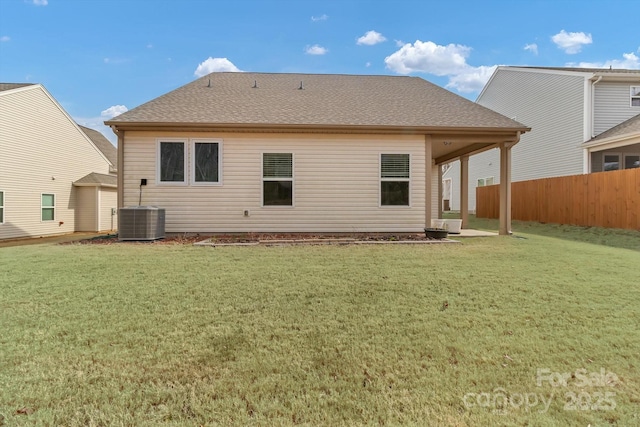 back of property with central AC and a lawn