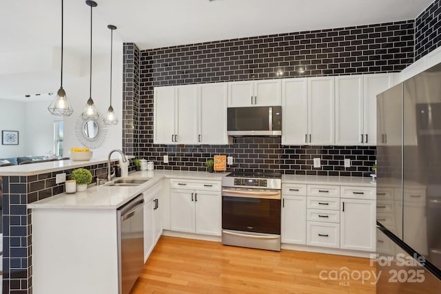 kitchen with pendant lighting, sink, stainless steel appliances, and kitchen peninsula