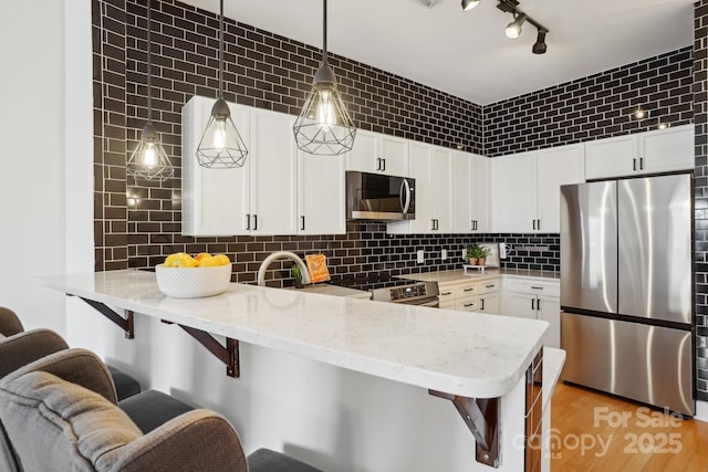 kitchen featuring pendant lighting, white cabinetry, stainless steel appliances, and kitchen peninsula