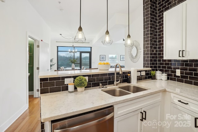 kitchen with white cabinetry, dishwasher, sink, and light stone counters