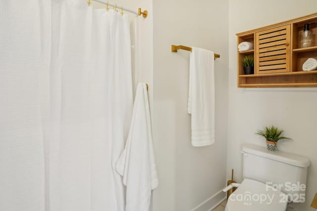 bathroom featuring toilet and a shower with shower curtain