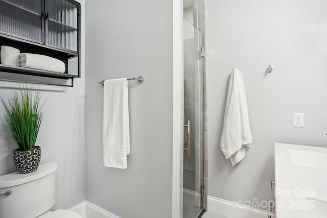 bathroom featuring vanity, a shower with shower door, and toilet