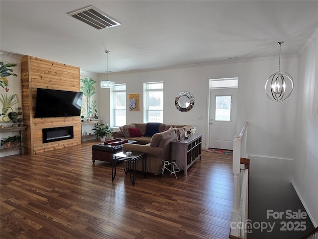 living room with a large fireplace, visible vents, dark wood finished floors, and crown molding