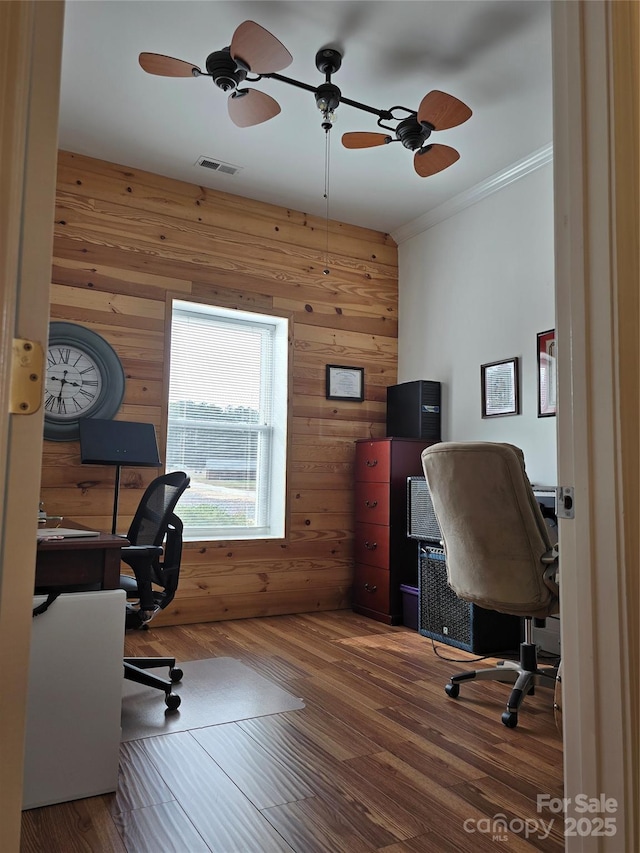 office space featuring visible vents, crown molding, wooden walls, and wood finished floors