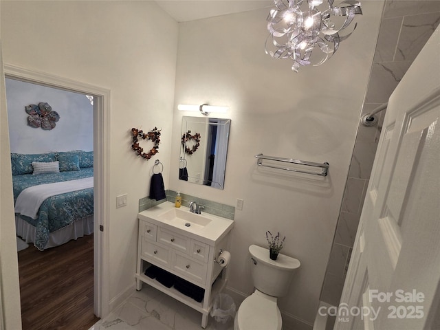 ensuite bathroom featuring ensuite bathroom, toilet, vanity, baseboards, and marble finish floor