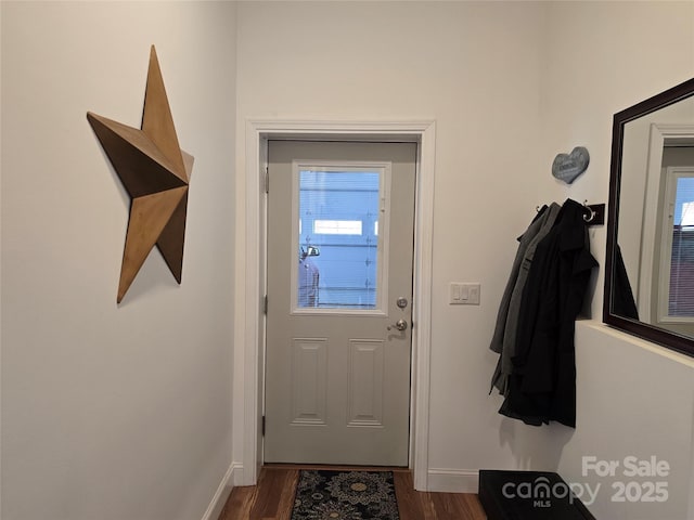 doorway to outside featuring baseboards and dark wood-style flooring