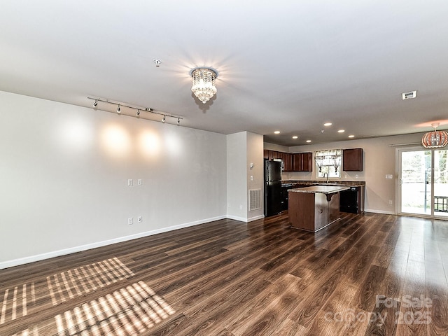 kitchen with a kitchen bar, dark hardwood / wood-style floors, black fridge, and a kitchen island