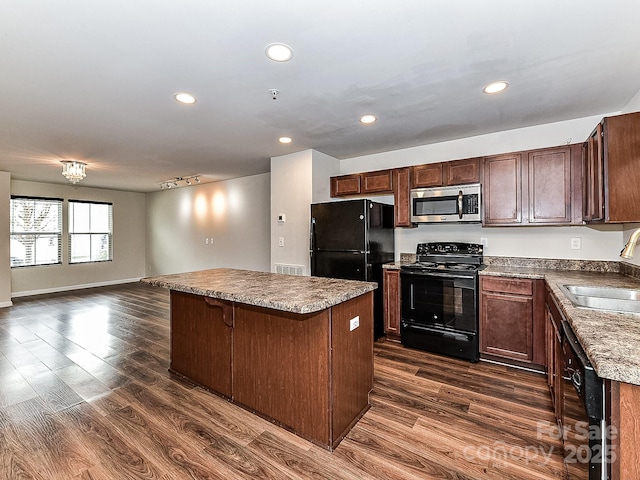 kitchen featuring dark wood-type flooring, sink, a kitchen breakfast bar, a kitchen island, and black appliances