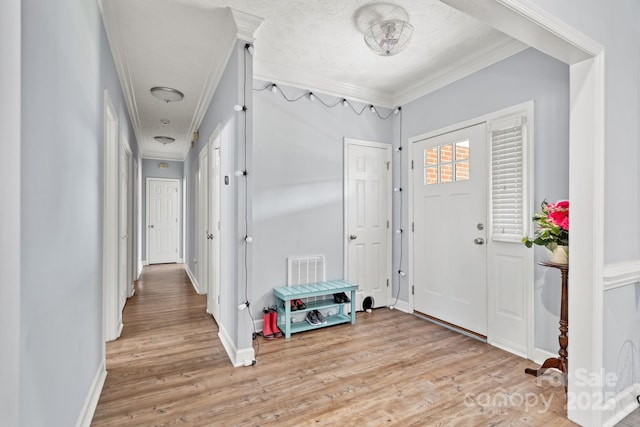 foyer entrance featuring crown molding, light hardwood / wood-style flooring, and a textured ceiling