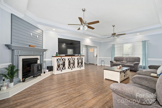 living room with a raised ceiling, ornamental molding, dark hardwood / wood-style floors, and ceiling fan