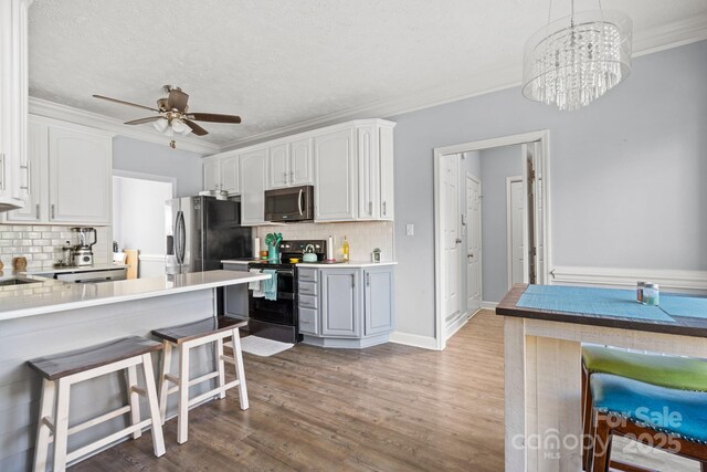 kitchen with a breakfast bar, white cabinetry, crown molding, appliances with stainless steel finishes, and pendant lighting