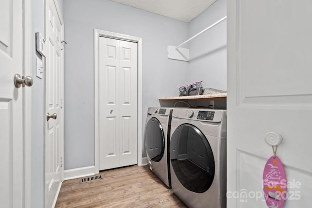 laundry room featuring independent washer and dryer, a textured ceiling, and light wood-type flooring