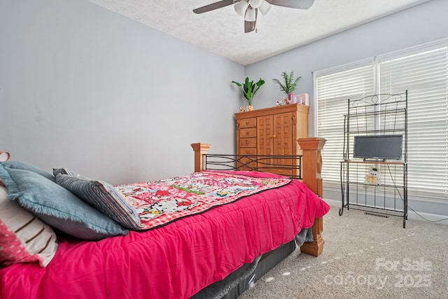 bedroom with ceiling fan, carpet, and a textured ceiling