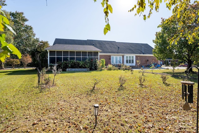 back of property with a sunroom and a yard