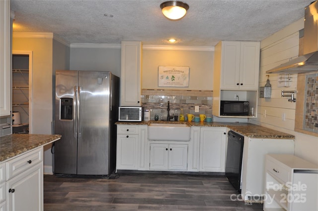 kitchen featuring black appliances, wall chimney range hood, sink, white cabinetry, and dark stone countertops