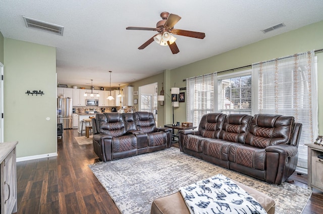 living room featuring ceiling fan, dark wood-type flooring, and a textured ceiling