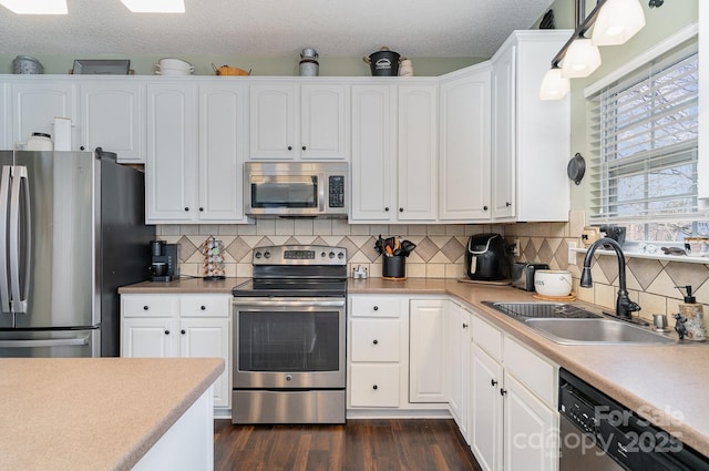 kitchen featuring white cabinetry, sink, decorative light fixtures, and stainless steel appliances