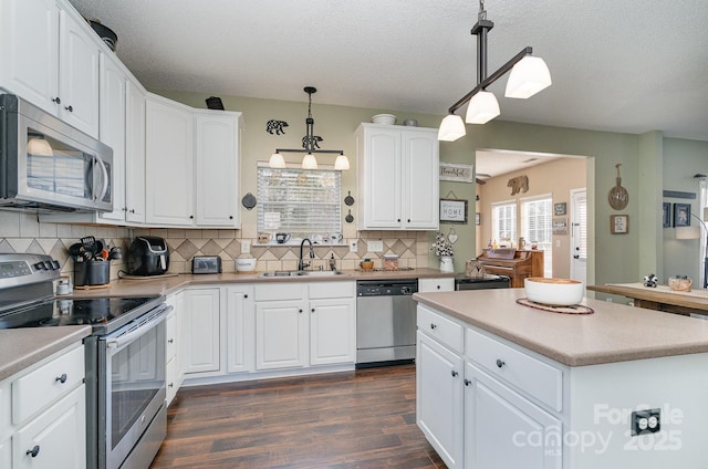 kitchen featuring dark hardwood / wood-style floors, decorative light fixtures, sink, white cabinets, and stainless steel appliances