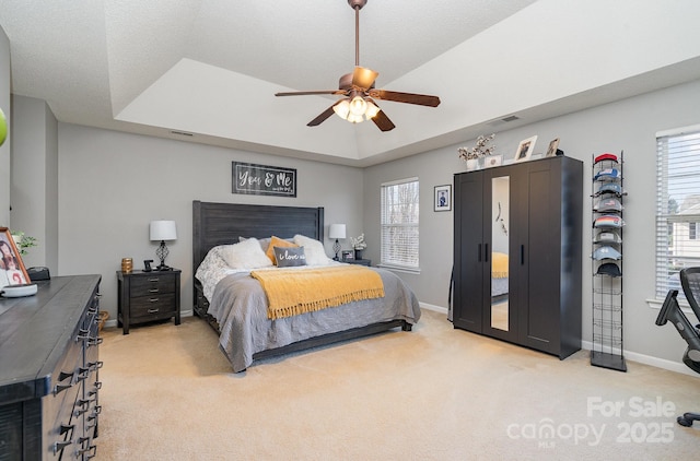 carpeted bedroom featuring ceiling fan and a raised ceiling