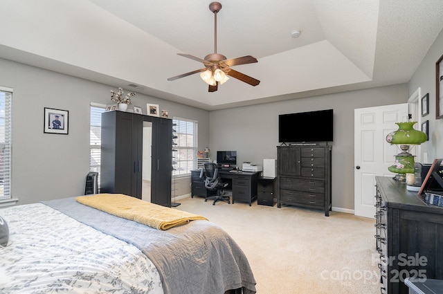 bedroom with a tray ceiling, light colored carpet, and ceiling fan