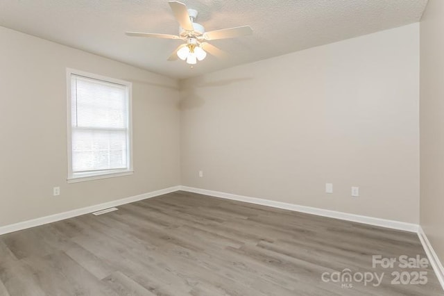 spare room featuring ceiling fan, dark wood-type flooring, and a textured ceiling