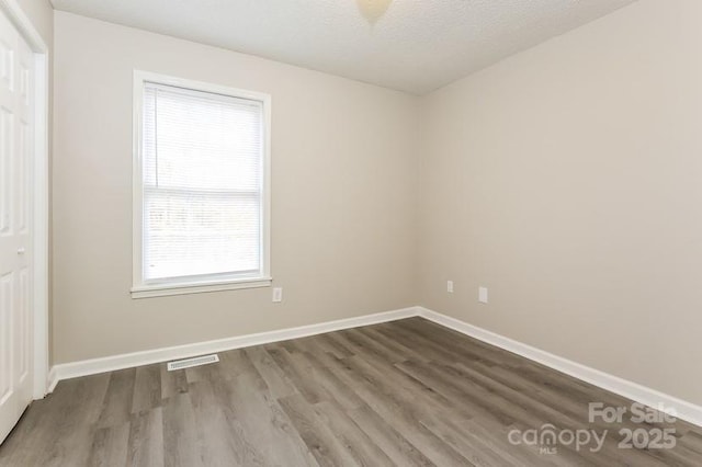 spare room with hardwood / wood-style floors and a textured ceiling