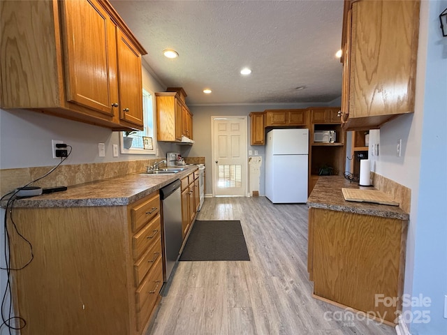 kitchen with sink, stainless steel appliances, light hardwood / wood-style floors, and a textured ceiling