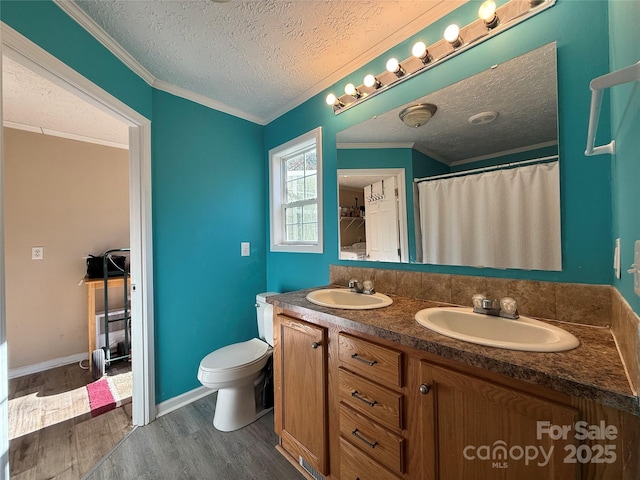 bathroom featuring toilet, crown molding, wood-type flooring, a textured ceiling, and vanity