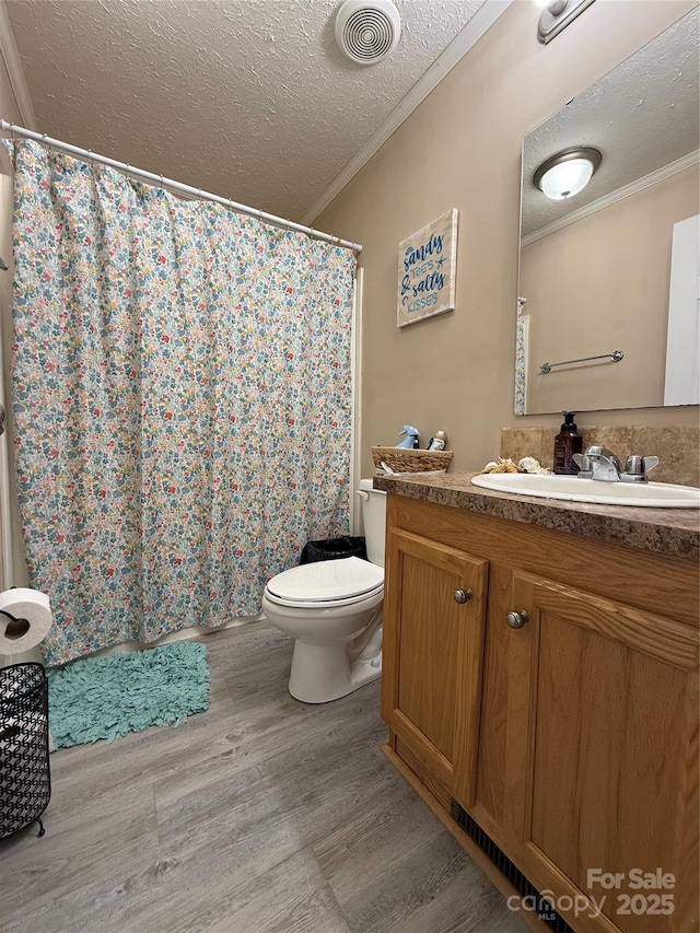 bathroom with crown molding, wood-type flooring, toilet, and a textured ceiling