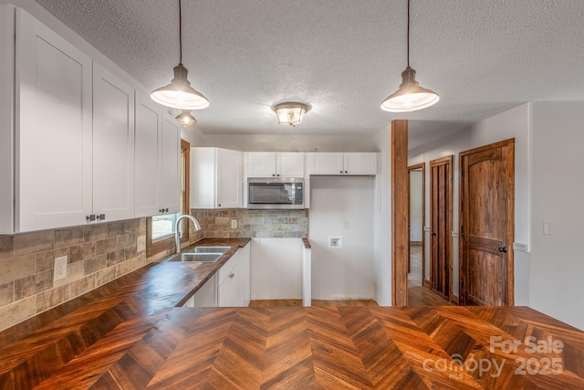 kitchen with sink, pendant lighting, and white cabinets