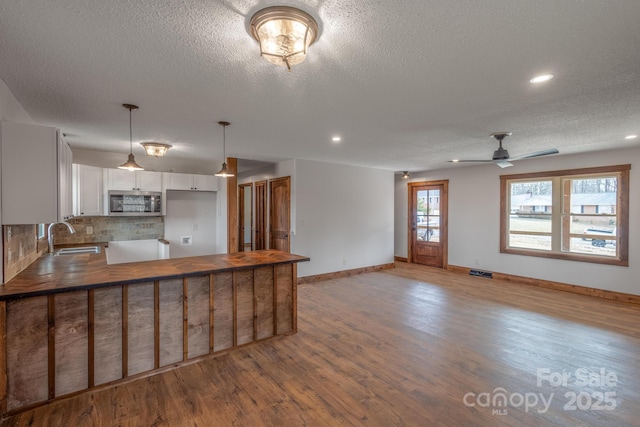 kitchen with tasteful backsplash, sink, white cabinets, and light wood-type flooring