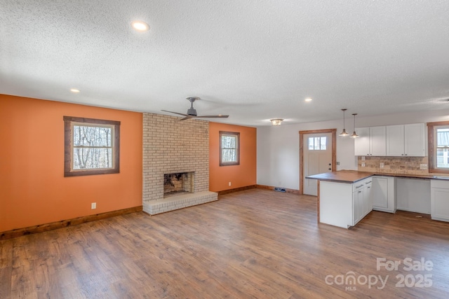 kitchen with white cabinetry, kitchen peninsula, hardwood / wood-style floors, and pendant lighting