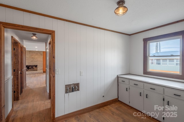 laundry area featuring hardwood / wood-style flooring, crown molding, and a textured ceiling