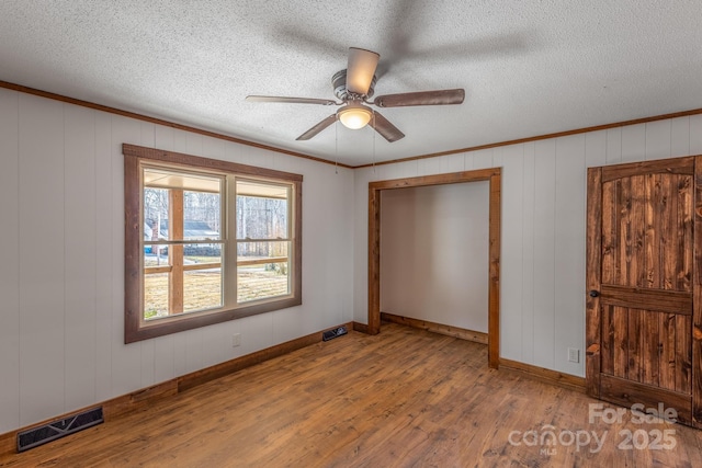 unfurnished bedroom with hardwood / wood-style flooring, crown molding, and a textured ceiling