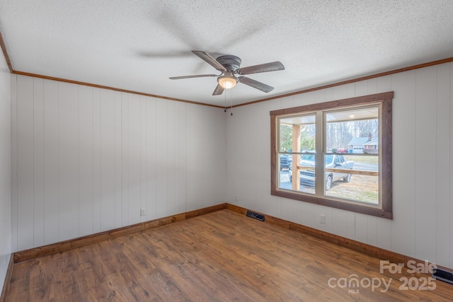 unfurnished room with ceiling fan, hardwood / wood-style flooring, ornamental molding, and a textured ceiling