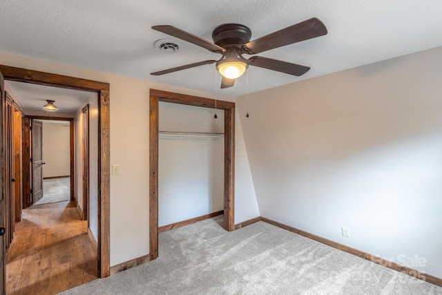 unfurnished bedroom with light carpet, ceiling fan, a closet, and a textured ceiling