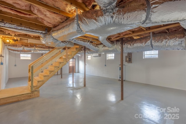 basement featuring electric panel, water heater, and a healthy amount of sunlight